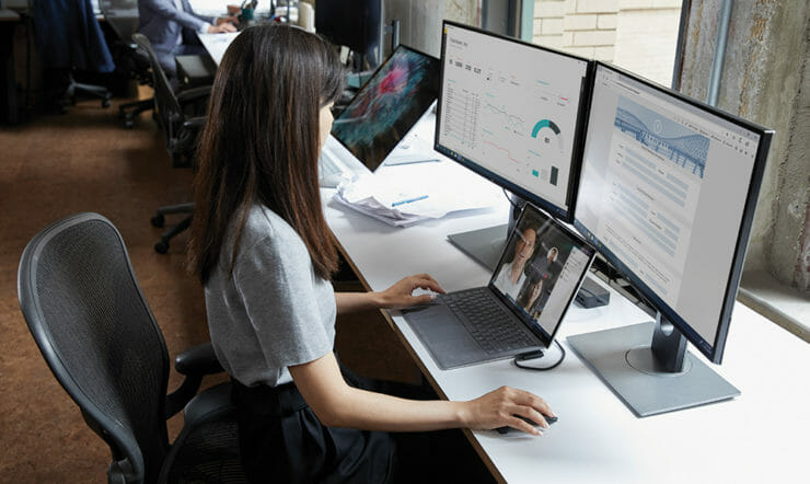 uma mulher sentada em uma mesa na frente de um computador portátil