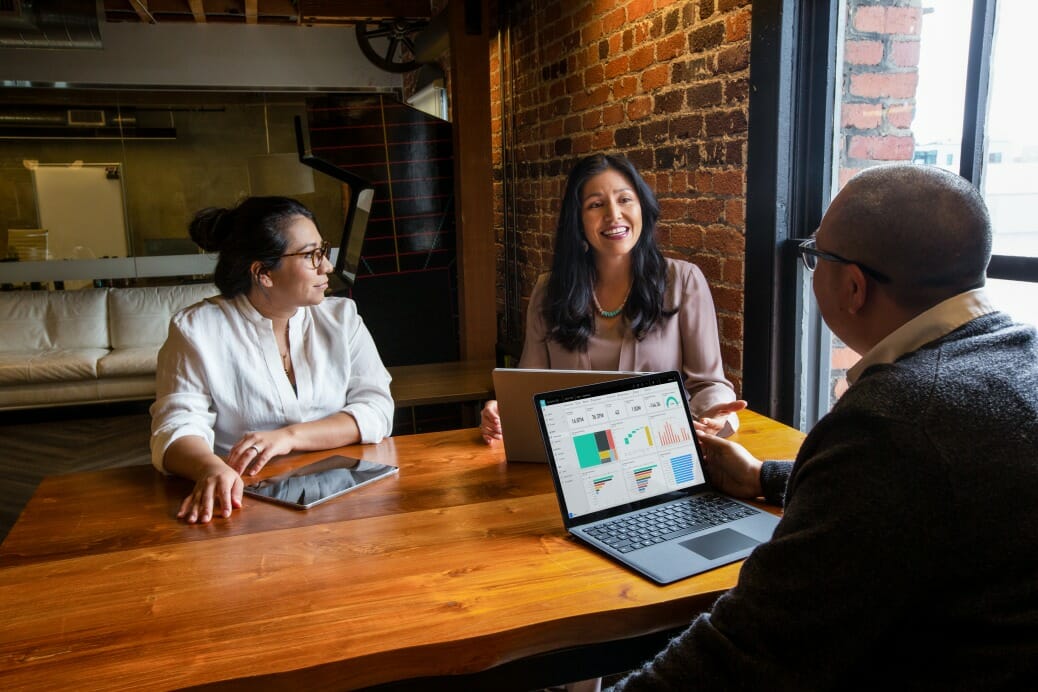 en gruppe mennesker, der sidder ved et bord ved hjælp af en bærbar computer