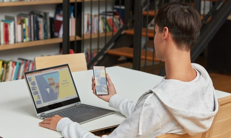 a boy using a laptop computer sitting on top of a table
