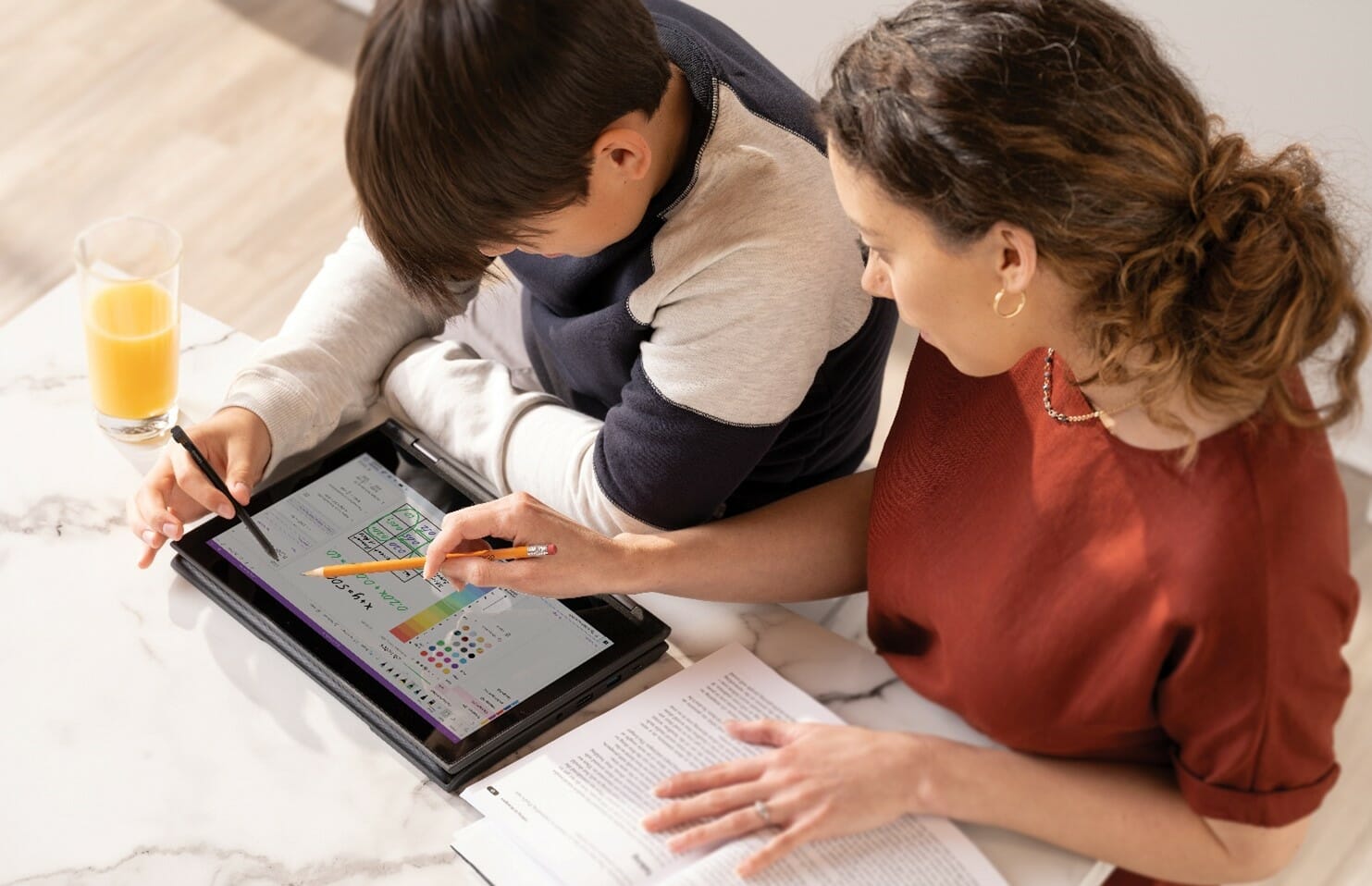 een jonge jongen die bij een lijst met behulp van een laptop zit