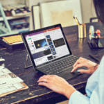 henkilö, joka istuu pöydässä kannettavan tietokoneen avulla