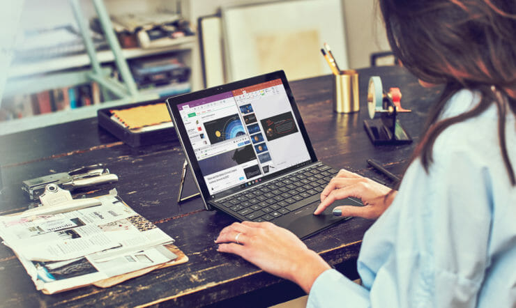 henkilö, joka istuu pöydässä kannettavan tietokoneen avulla