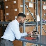 een mens die bij een lijst zit die laptop gebruikt