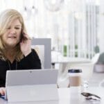 en kvinde sidder ved et bord ved hjælp af en bærbar computer