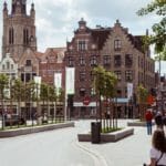 een groep mensen die onderaan een straat naast hoge gebouwen lopen