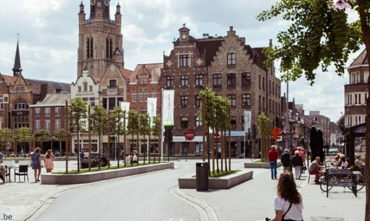 een groep mensen die onderaan een straat naast hoge gebouwen lopen