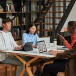 een persoon die een laptopcomputer gebruikt die bovenop een boekplank zit