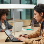 een mensenzitting bij een lijst die een laptopcomputer met behulp van