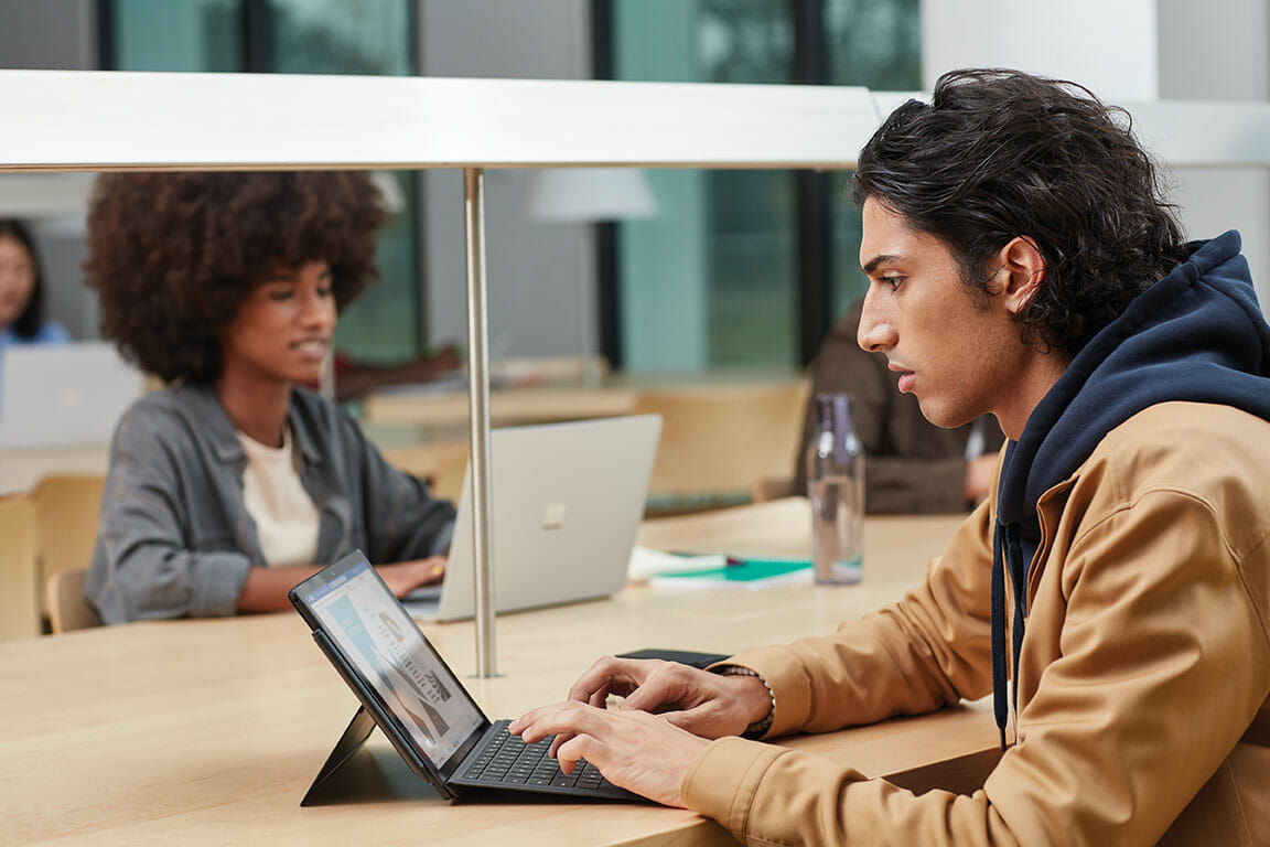 een mensenzitting bij een lijst die een laptopcomputer met behulp van