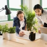 a group of people sitting at a table using a laptop computer