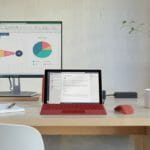 een bureau met een laptopcomputer die bovenop een houten lijst zit