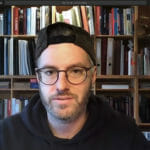 en mand, der sidder foran en boghylde