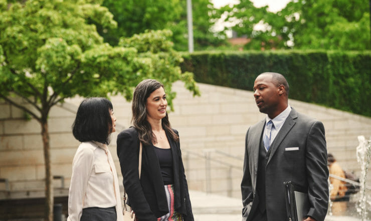 een groep mensen die zich naast een persoon in een kostuum en band bevinden
