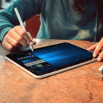 een persoon die aan een lijst met behulp van een laptop zit