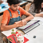 een groep mensen die aan een lijst met behulp van een laptop zitten