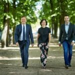 en gruppe mennesker som står ved siden av en mann i dress og slips