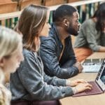 students behind desk with laptop