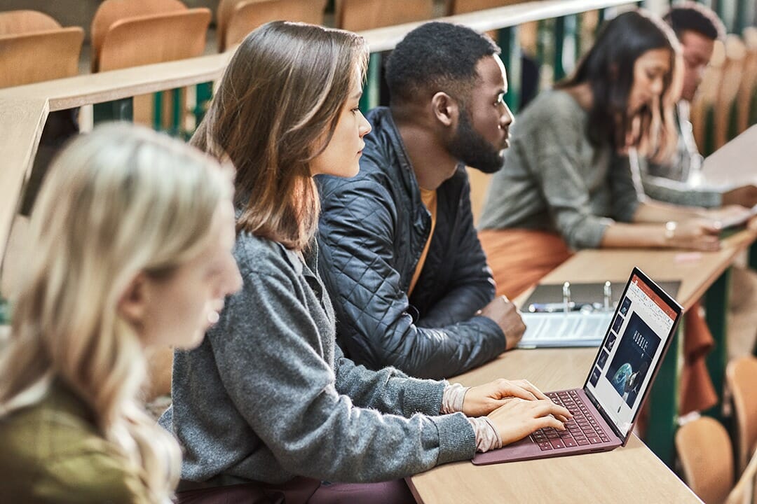 students behind desk with laptop