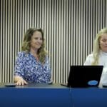 two women in front of a desk