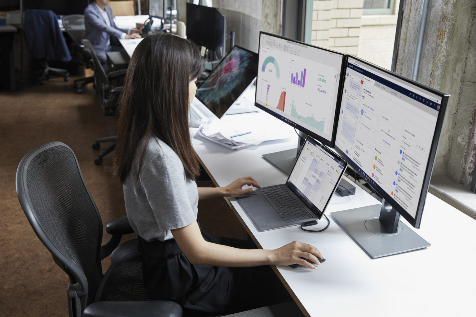 woman in front of two screens and a laptop