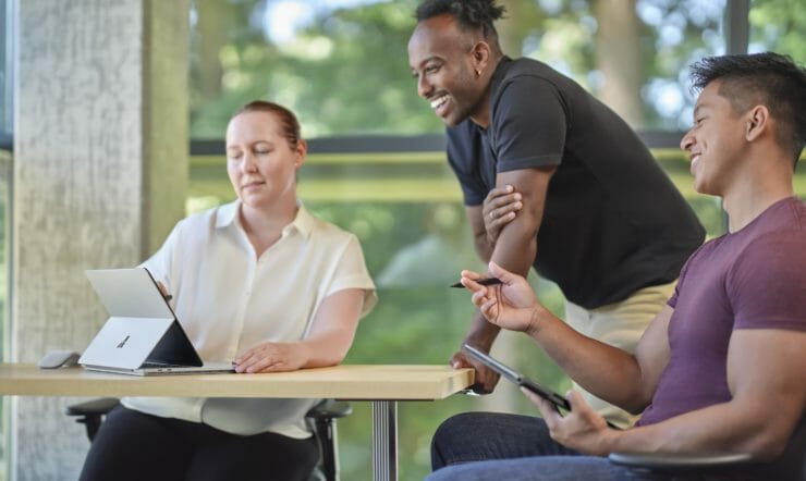 Two students and a teacher are looking at a Surface Laptop Studio.