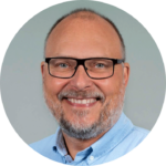 a man with glasses smiling 