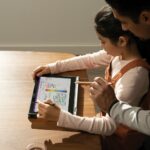 Un padre supervisa a su hija mientras navega con su dispositivo Windows