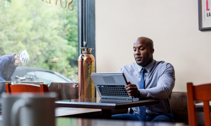 Man in suit sitting in cafe with a laptop
