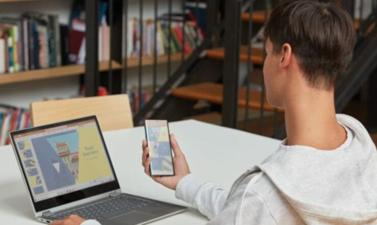 One person next to laptop holding phone