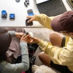 Kaksi henkilö työpöydän ääressä tutkimassa erilaisia saavutettavuusapuvälineitä